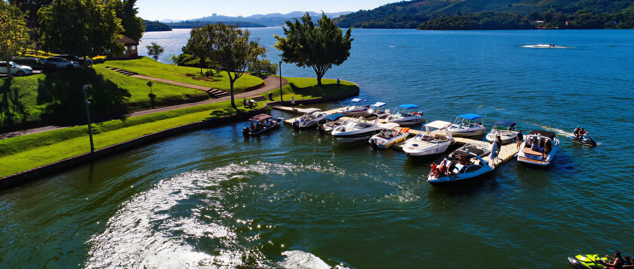 Marina do Pier 22 com lanchas atracadas, uma embarcação saindo e jet skis na represa
